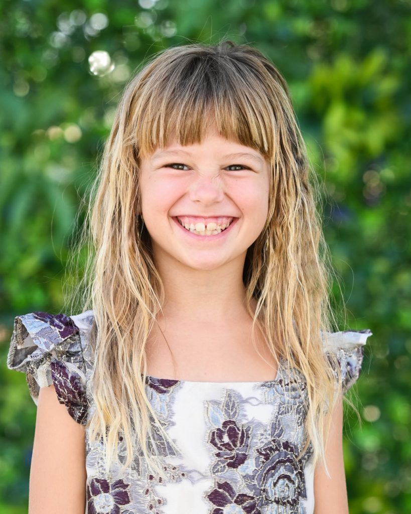 a girl smiling in brown and white dress